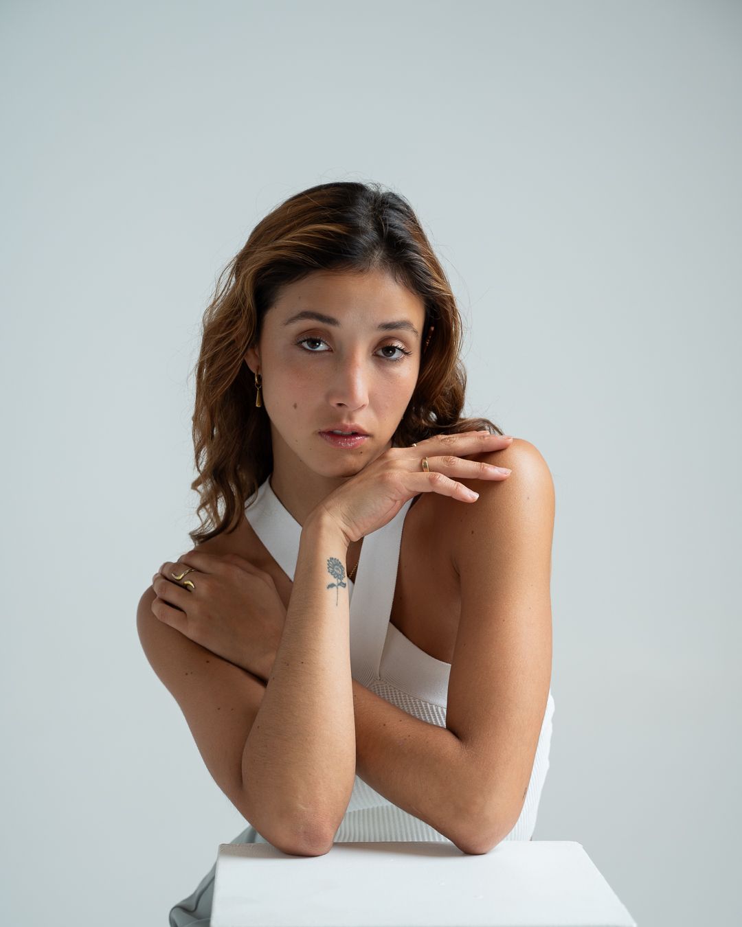 A series of minimalist studio portraits showing artistic poses against a light gray background.