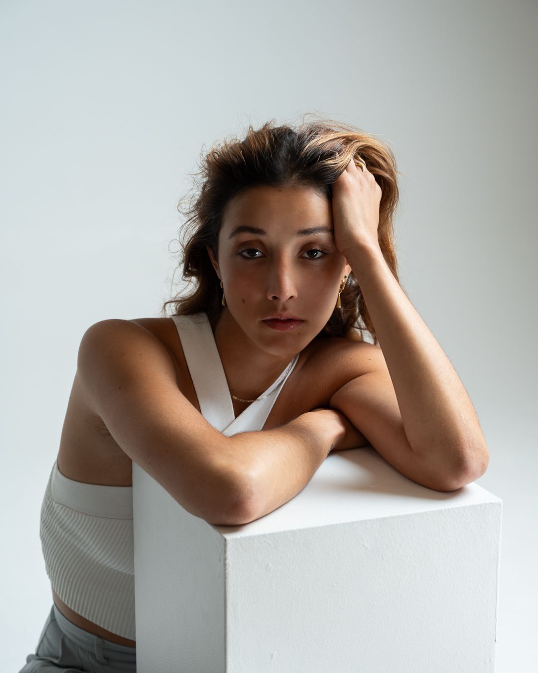 Artistic portrait series showing a figure in white posing against a minimalist backdrop with dramatic shadows.
