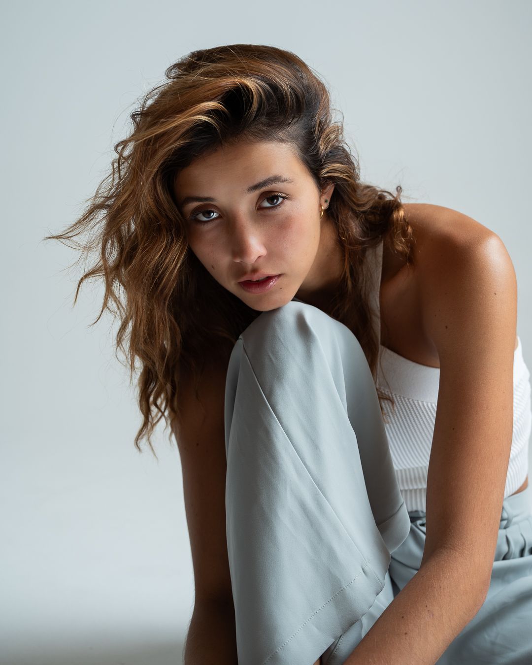 Fashion model poses in white sleeveless top against light background in dynamic motion series.