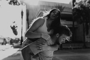 A joyful piggyback ride captured in black and white on a sunny street.