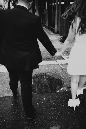Black and white shot of a couple walking together on textured pavement.