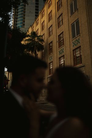 Silhouetted figures against an illuminated urban building facade at night.