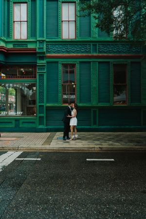 Art gallery exterior with green painted storefront and large windows on a rainy day.