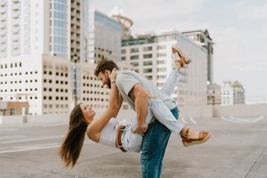 A couple dances in an urban setting with tall buildings in the background, creating a romantic atmosphere.