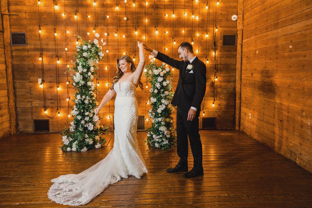 Rustic barn wedding venue decorated with warm string lights and Christmas trees creating a cozy winter atmosphere.