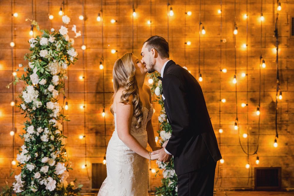 Wedding celebration scene with romantic string lights and floral arrangements creating a warm, intimate atmosphere.