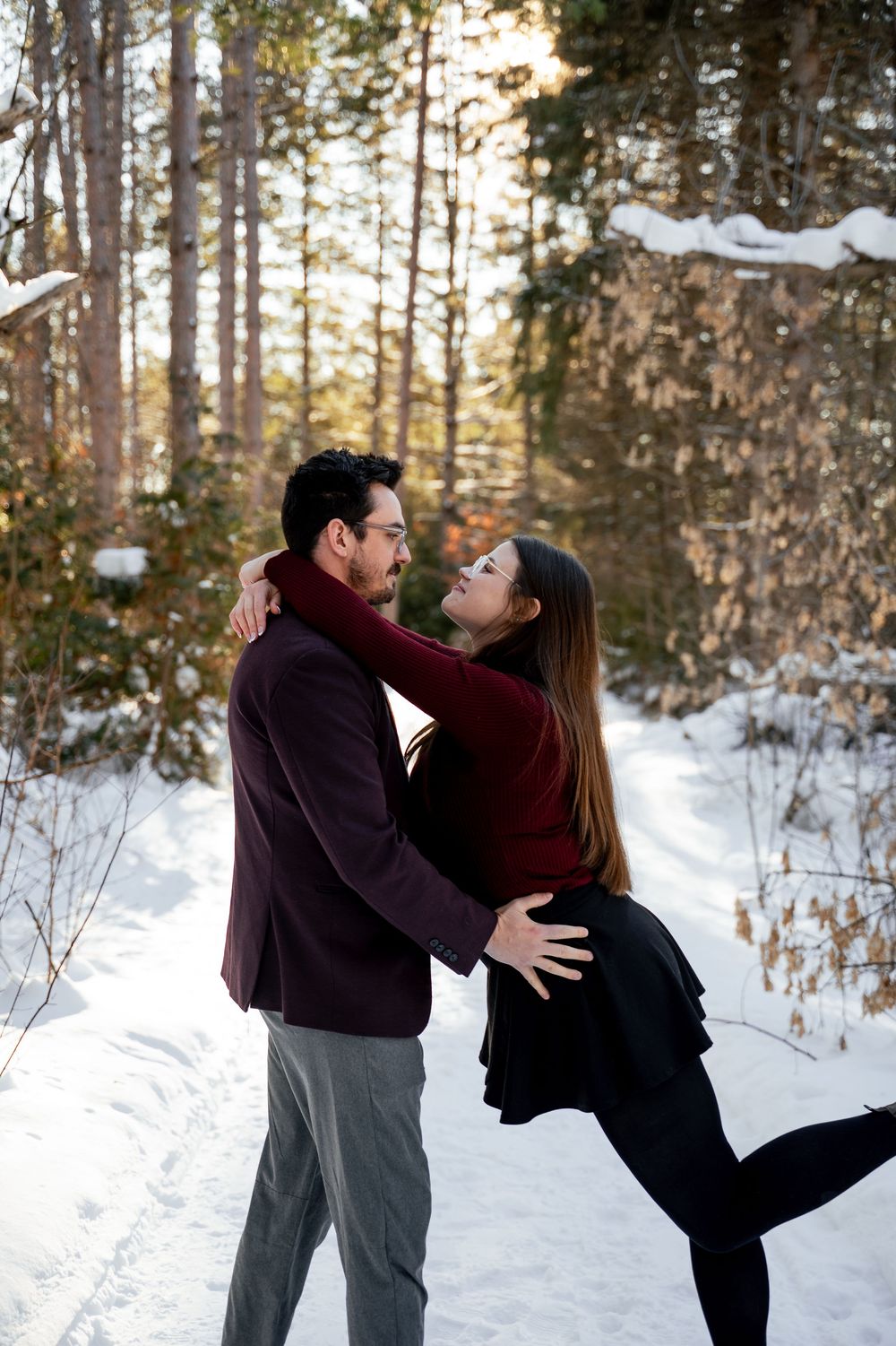 Romantic couple dancing and embracing in a snow-covered forest setting.