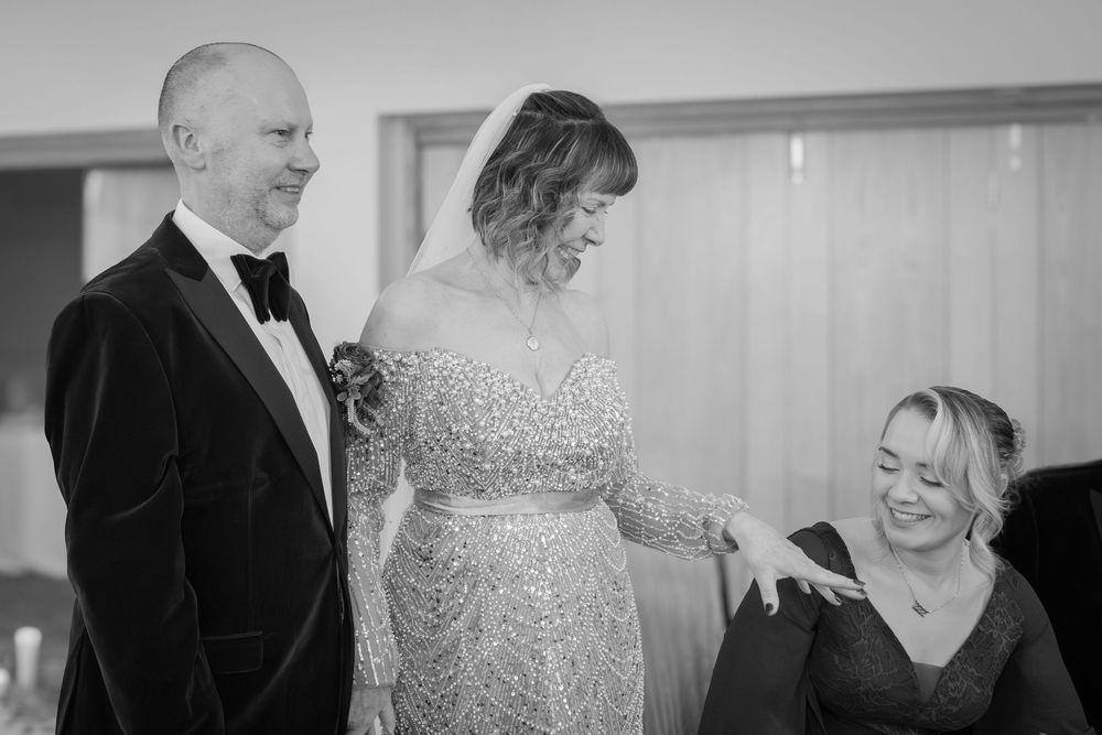 A candid black and white moment at a formal event showing three people sharing a joyful interaction.