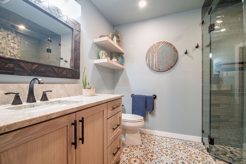 Spacious bathroom renovation with custom wood cabinetry and seamless glass shower enclosure in Boerne.