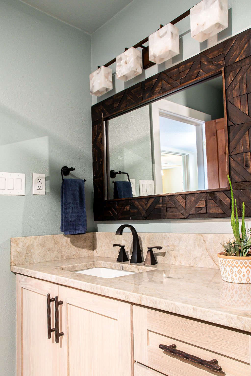 Elegant bathroom vanity with white shaker cabinets, marble countertops, and twin wood-framed mirrors.