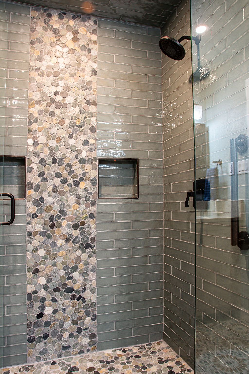 Modern bathroom shower featuring a custom mosaic tile accent wall and frameless glass door.