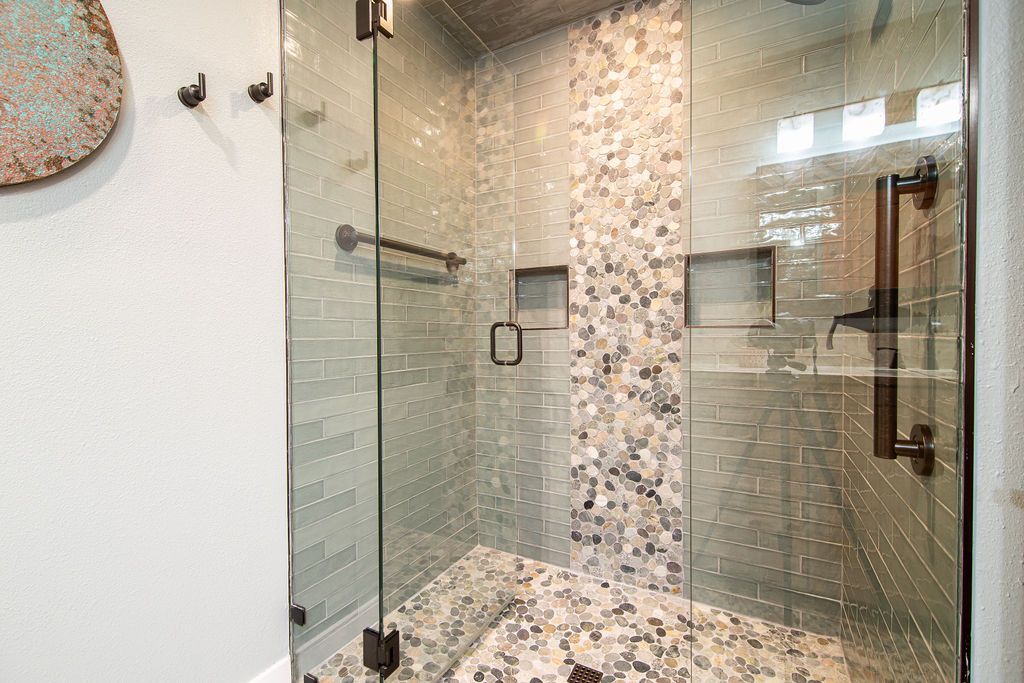 Modern bathroom shower featuring a custom mosaic tile accent wall and frameless glass door.
