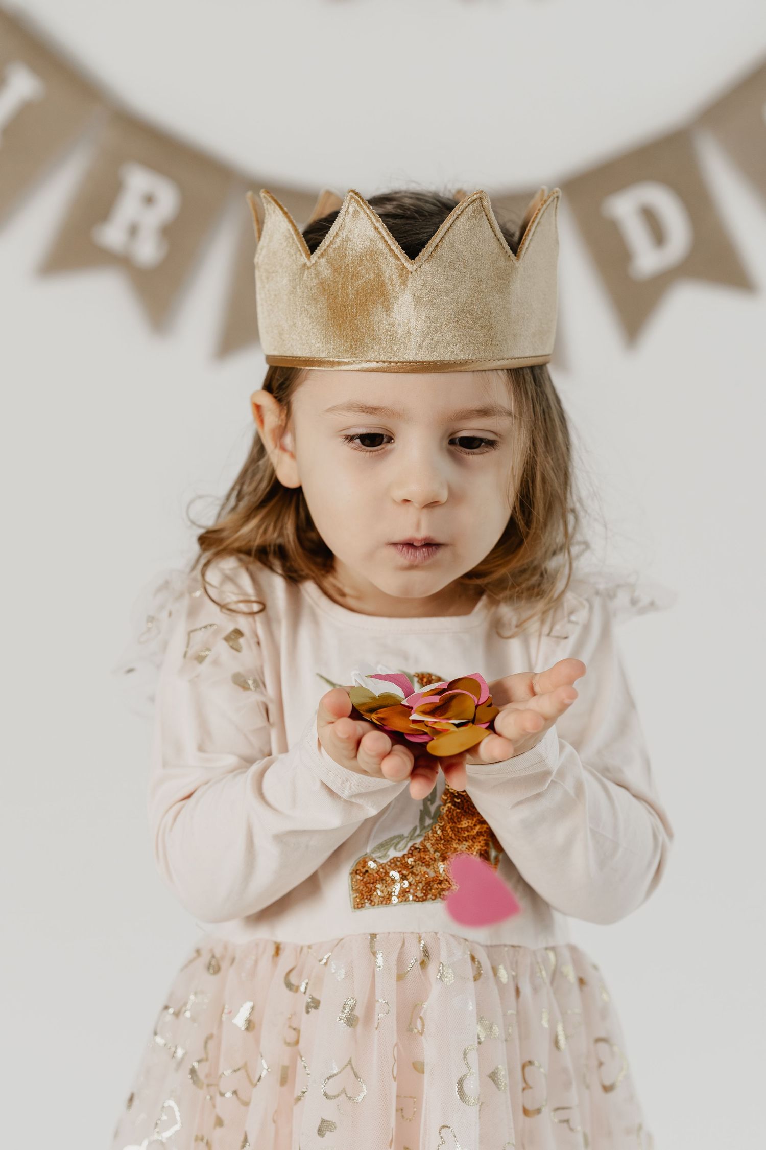 Geburtstagskind Mädchen pustet Konfetti beim Geburtstagsfotoshooting im Fotostudio Stockerau