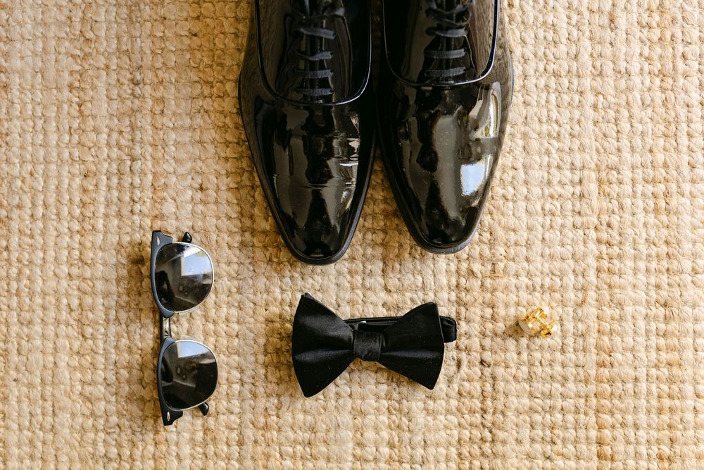 groom details flat lay against a beige carpeted wall