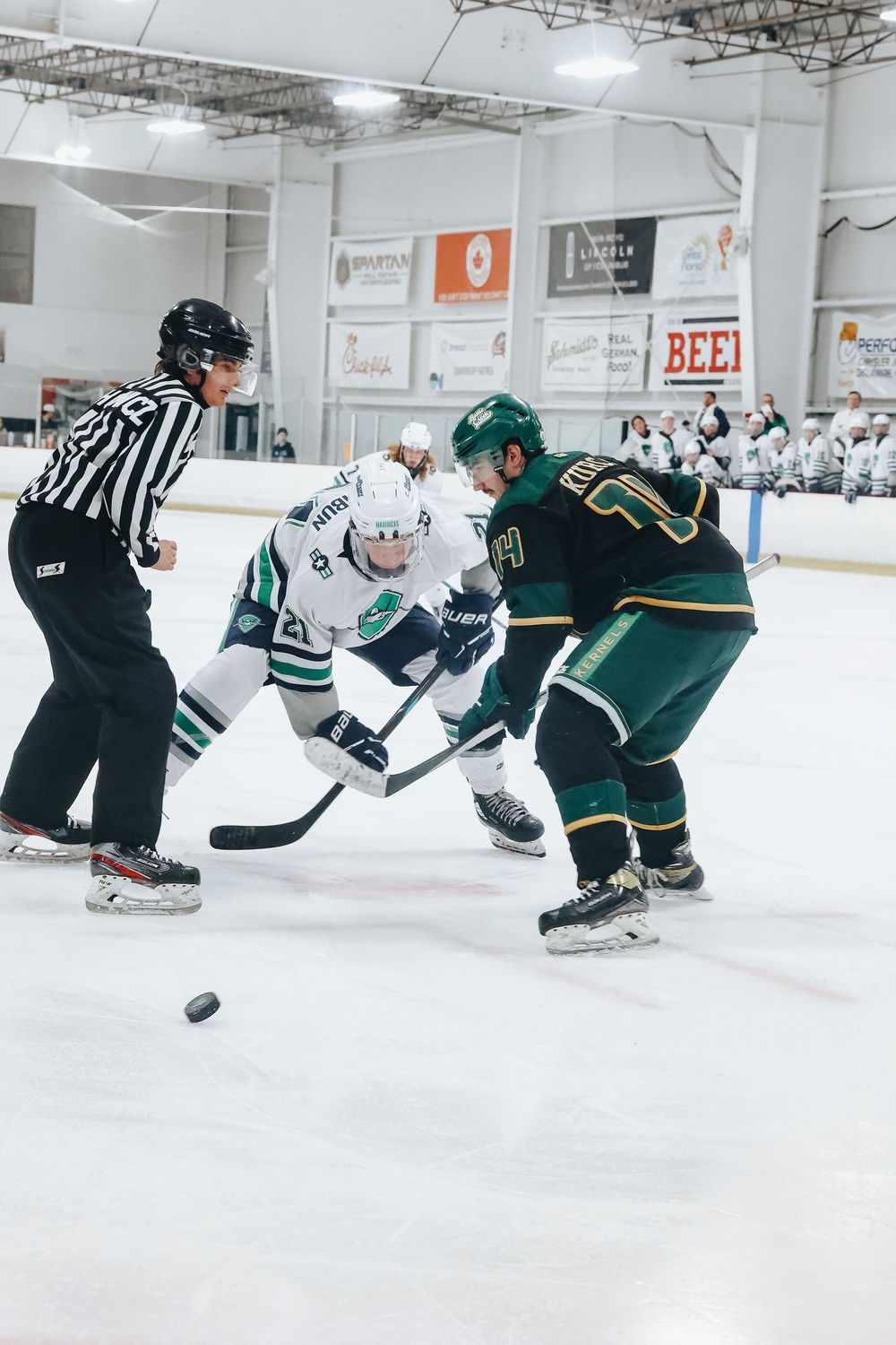 Hockey players from opposing teams face off on the ice during an indoor match.