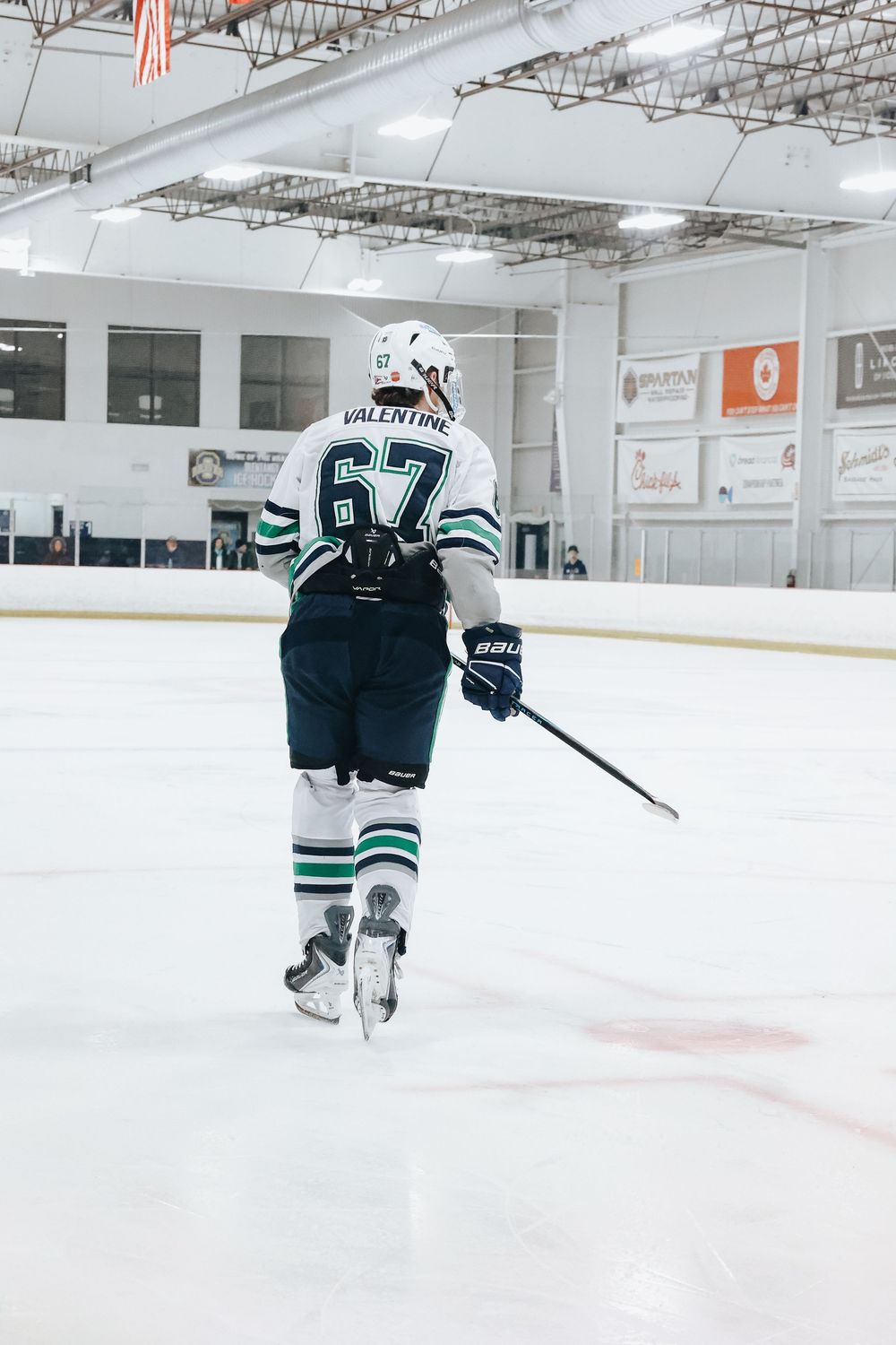 Hockey player in white jersey number 67 skates on ice during game.