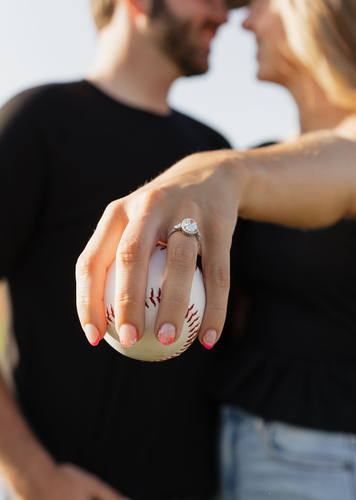 Close-up view of a hand displaying festive baseball-themed nail art with red stripes on white polish.