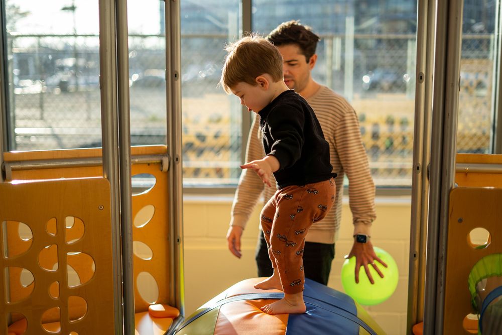 Children and caregivers participate in activities at an indoor play center with large windows and colorful decor.