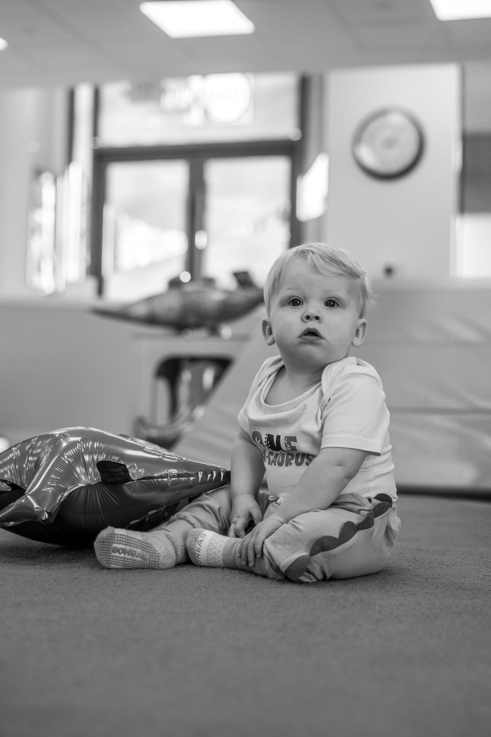 A series of black and white photos showing a baby lying on the floor in different positions.