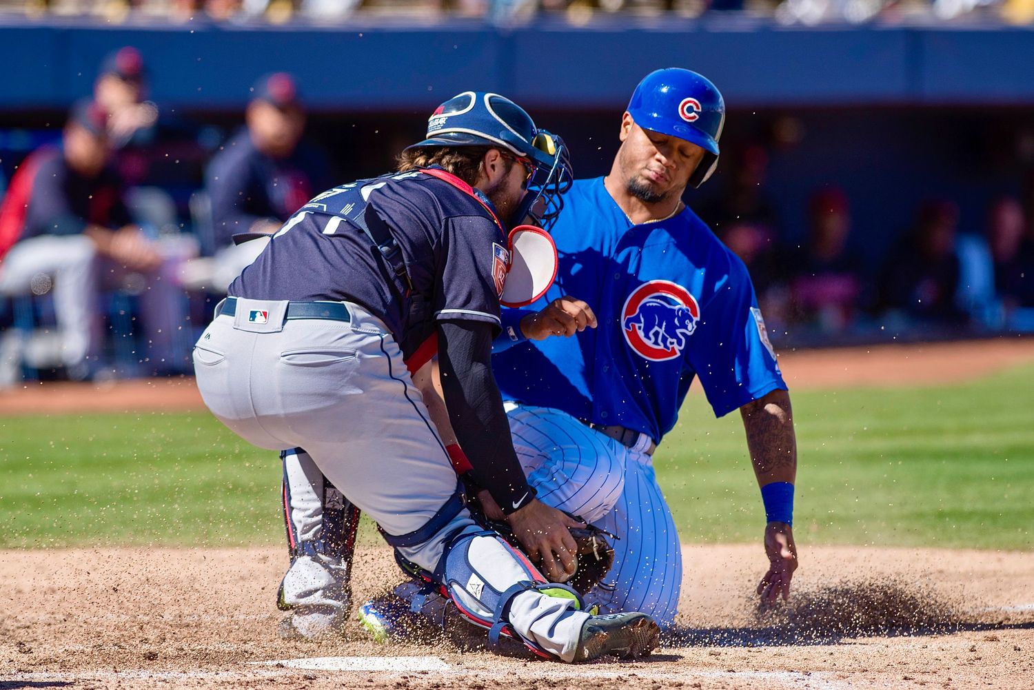 Baseball players collide at home plate during sliding play with catcher attempting tag.