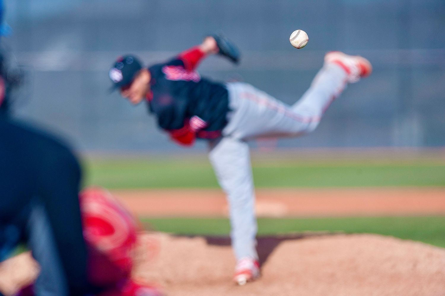 Baseball pitcher captured mid-motion in blurred artistic action shot.