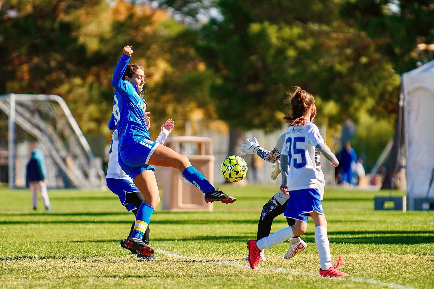 Youth soccer players competing for ball control during outdoor match.