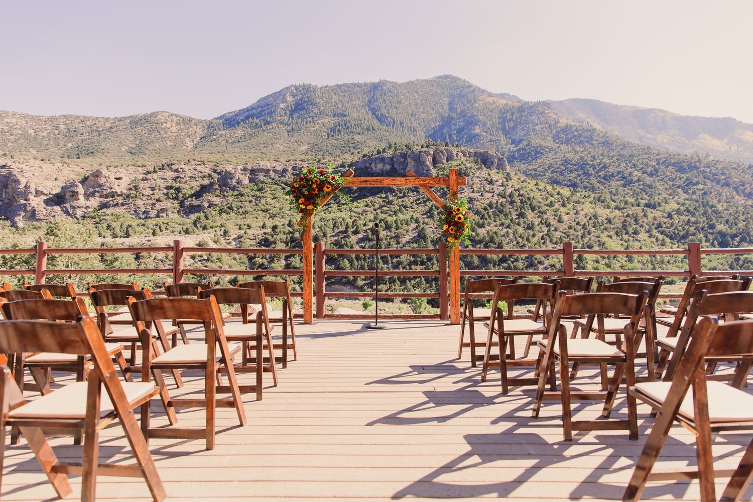 Outdoor wedding ceremony on a wooden deck with floral arch overlooking mountain landscape at Retreat on Charleston Peak.