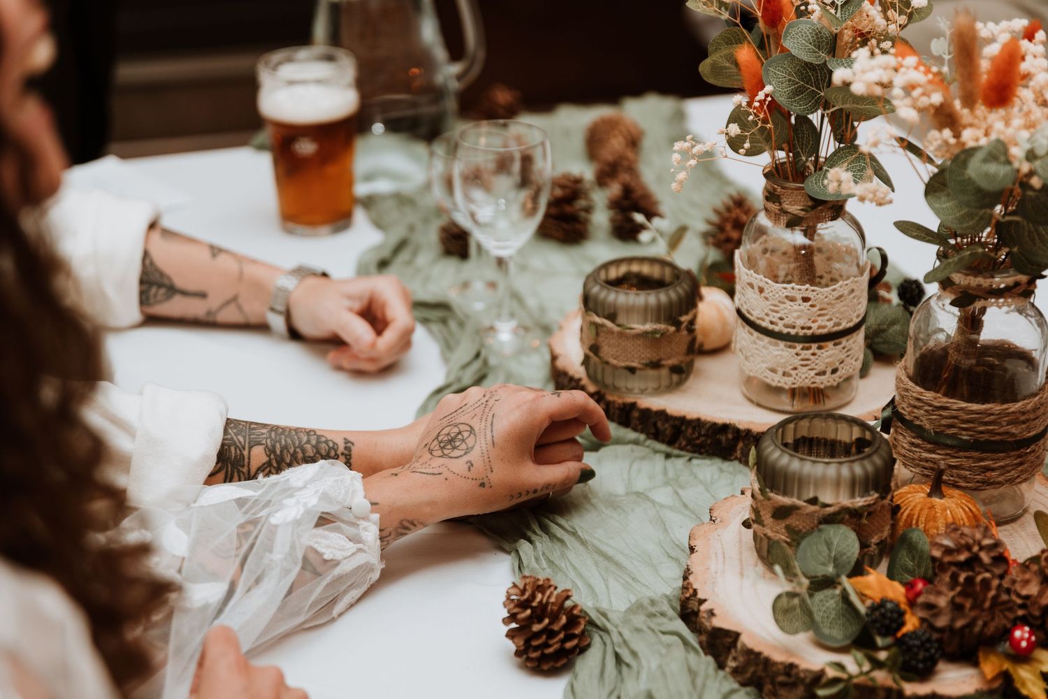A rustic autumn wedding reception table decorated with pinecones, flowers, and wooden accents.