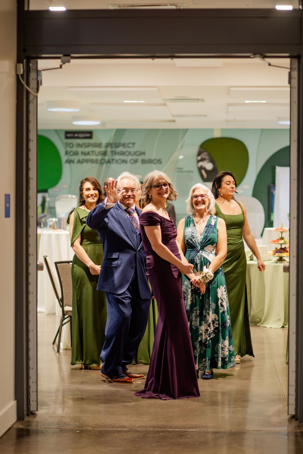 Wedding reception venue with guests mingling and dancing in an indoor space with green wall accents.