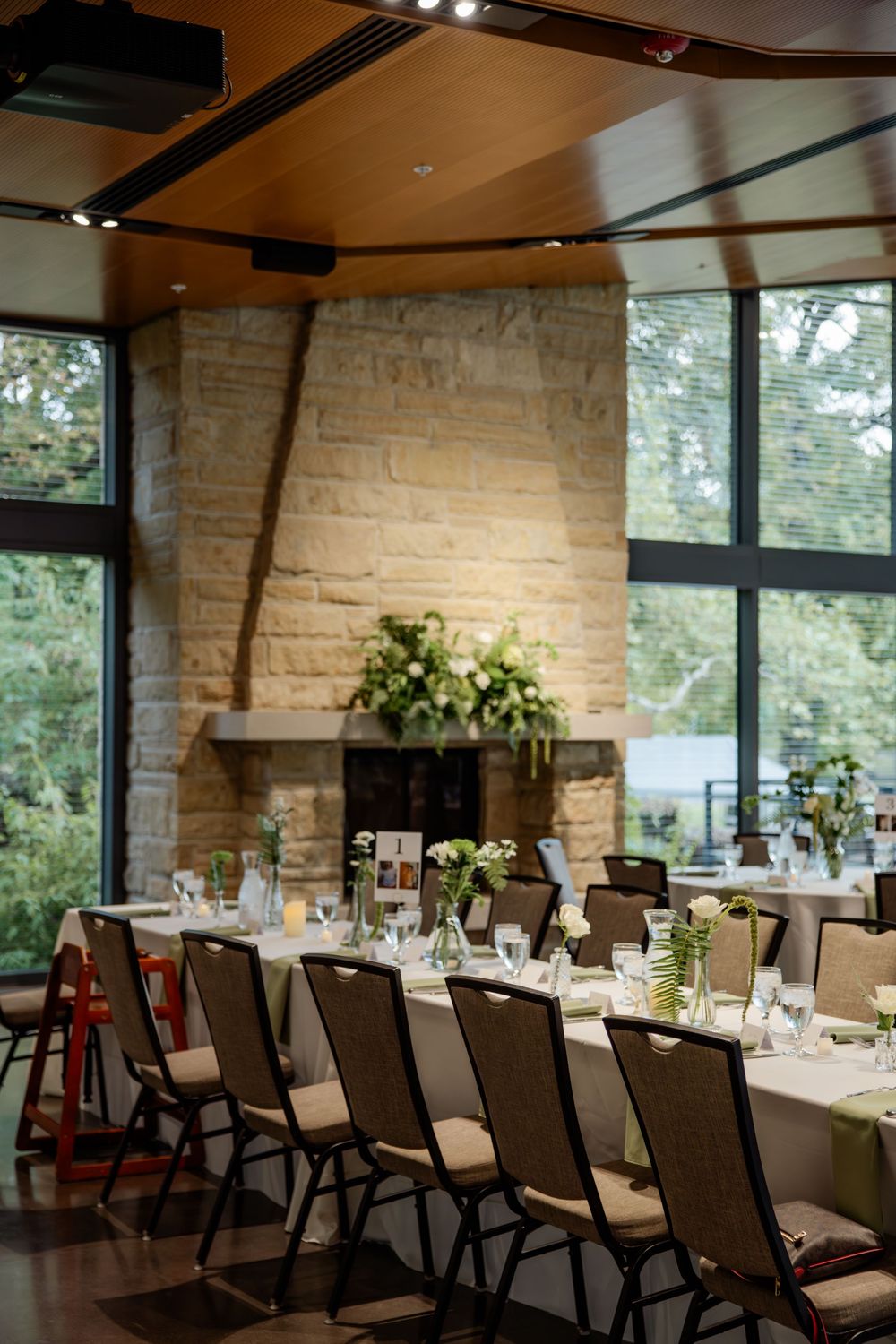 Elegant restaurant interior with stone walls, large windows, and tables set for fine dining in warm lighting.