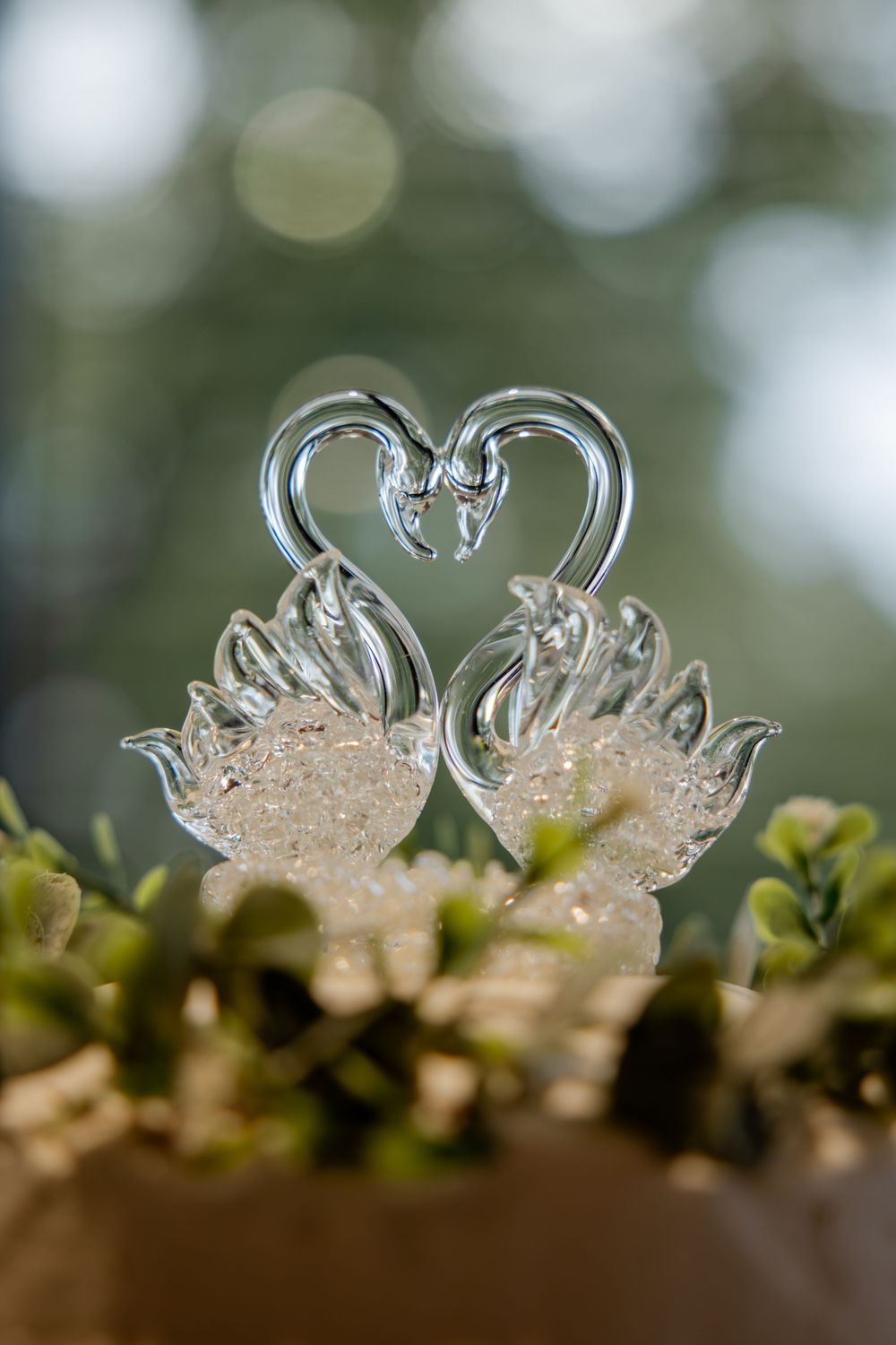 A close-up macro shot of a delicate glass swan figurine with bokeh effect in the background.