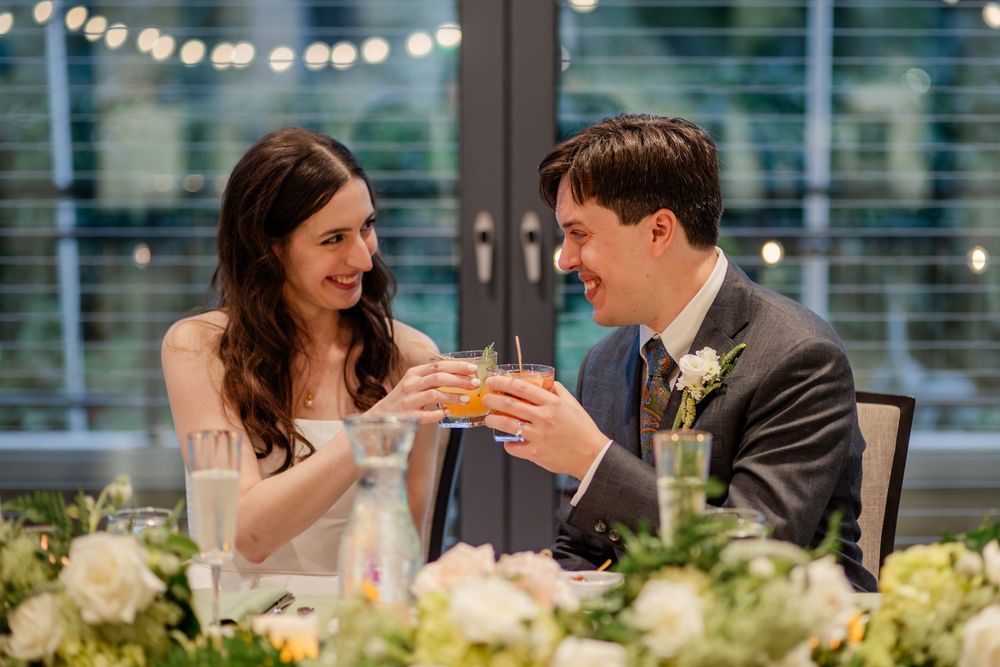 A couple shares a romantic moment at an elegant wedding reception under string lights and floral decorations.