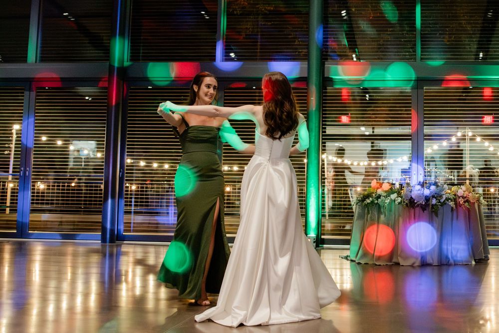 Wedding dresses on display in a brightly lit store window with colorful LED lighting creating a festive atmosphere.