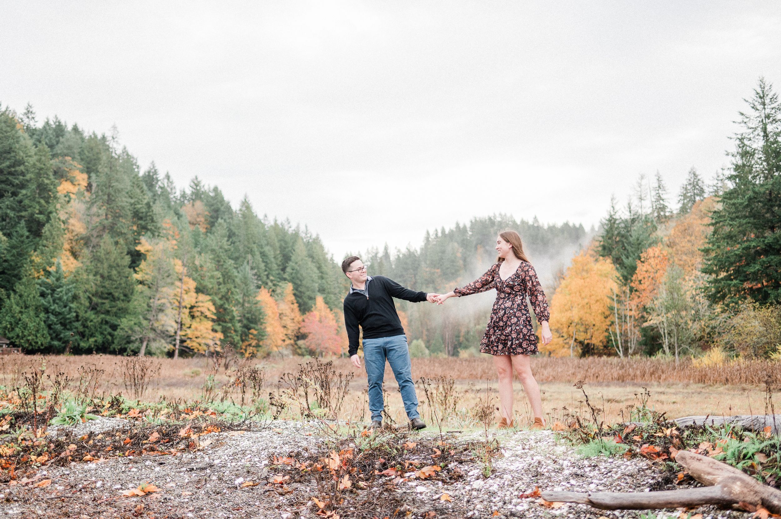 A couple walks through fallen autumn leaves in a scenic forest setting. Photo by Pine + Vow