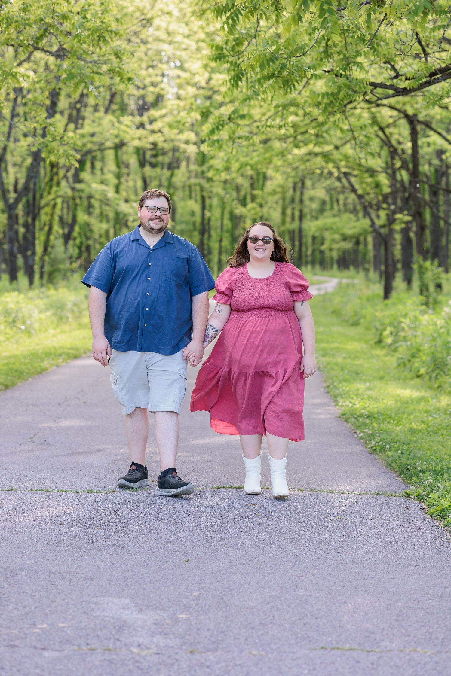 A couple walks together on a tree-lined path wearing coordinating blue and pink outfits in springtime.
