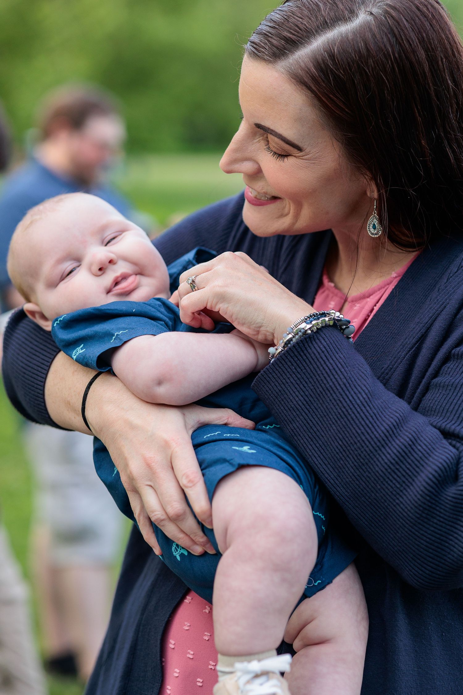 A baby wearing a blue outfit being held by grandma outdoors in a series of candid moments.