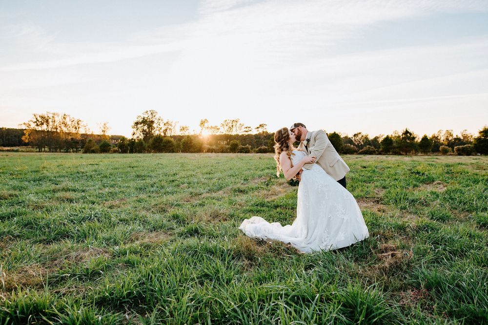 Bride in flowing white dress twirls gracefully across a sunlit meadow at golden hour.