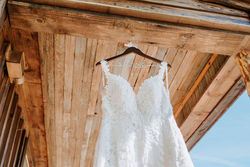 Rustic wooden barn exterior with white trim and overhanging roof against a bright blue sky.