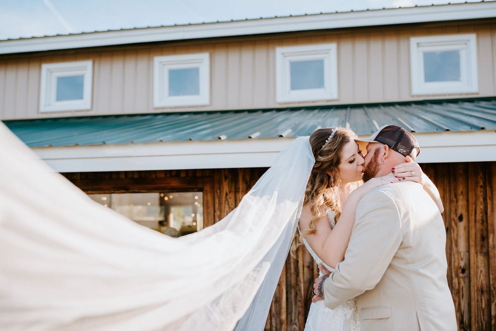 White wedding veil flows in the breeze against rustic barn wood siding.