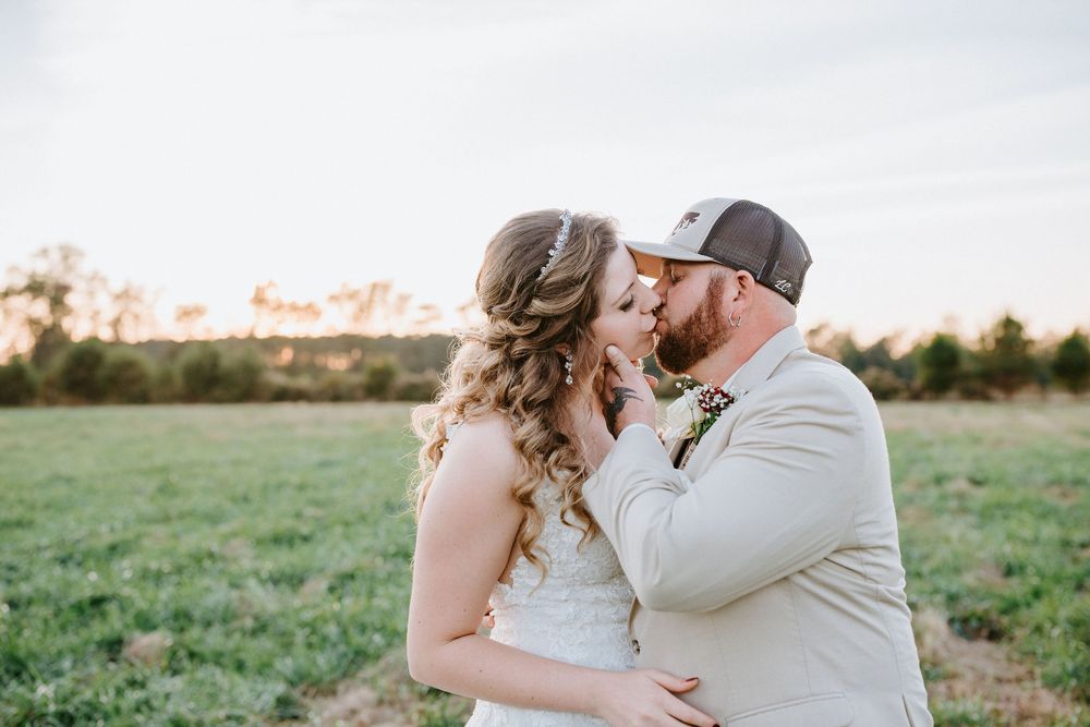 Romantic couple embracing in a sunlit field during sunset wedding photoshoot.