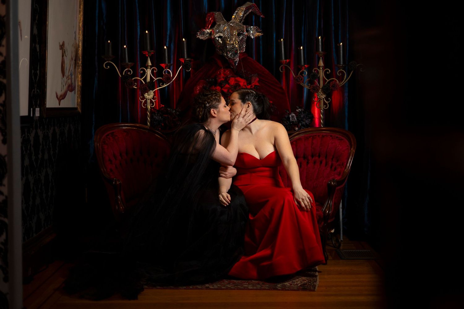 A romantic scene with a red velvet sofa and candelabra in a dark, moody setting with dramatic lighting.