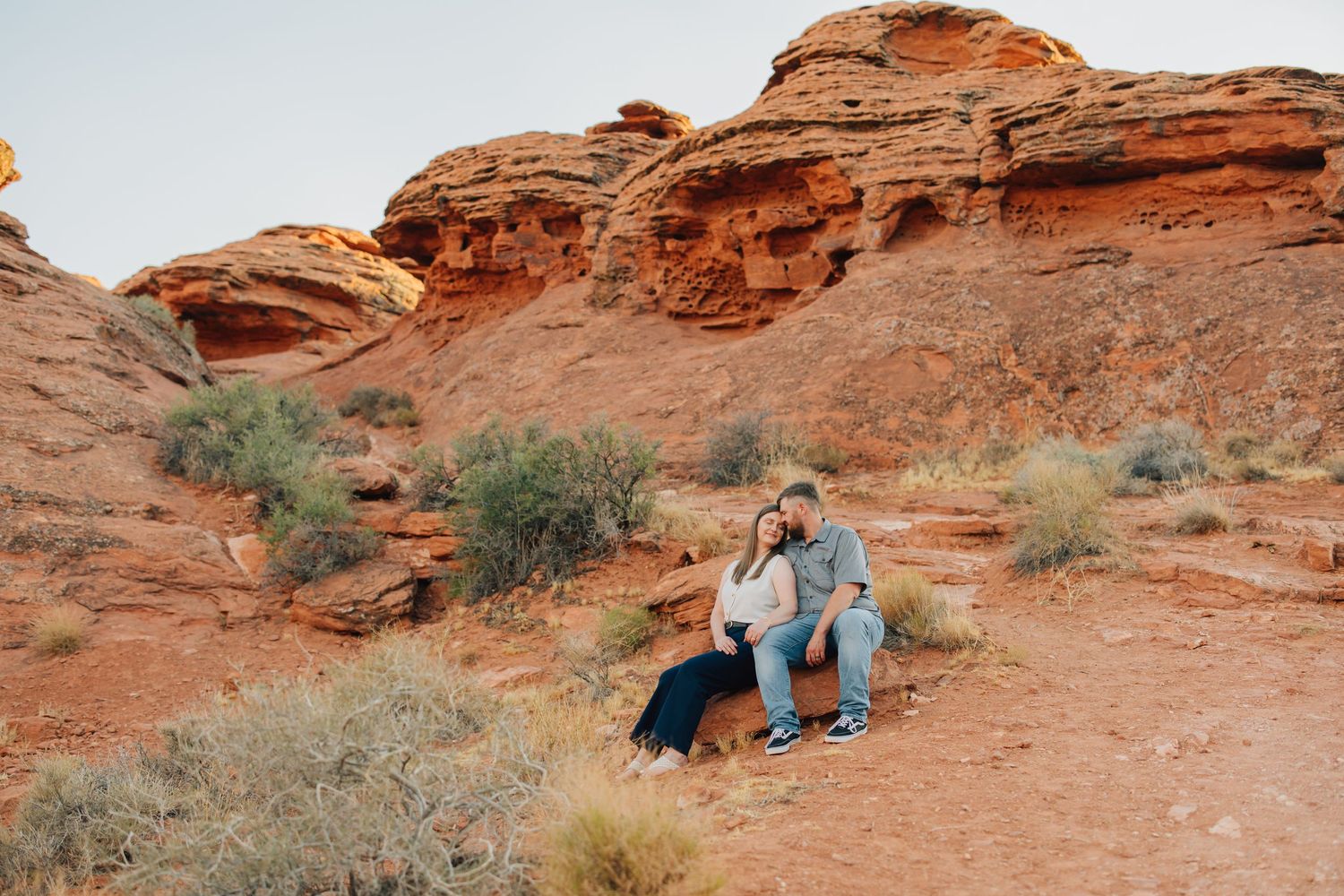 Couple sharing tender moments against stunning red rock formations in Valley of Fire State Park during sunset.