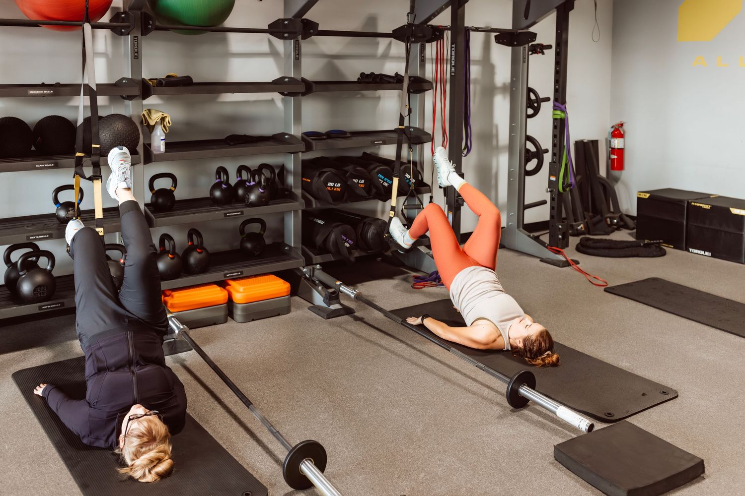 Person demonstrating proper form for glute bridge exercise on exercise mat in gym setting.