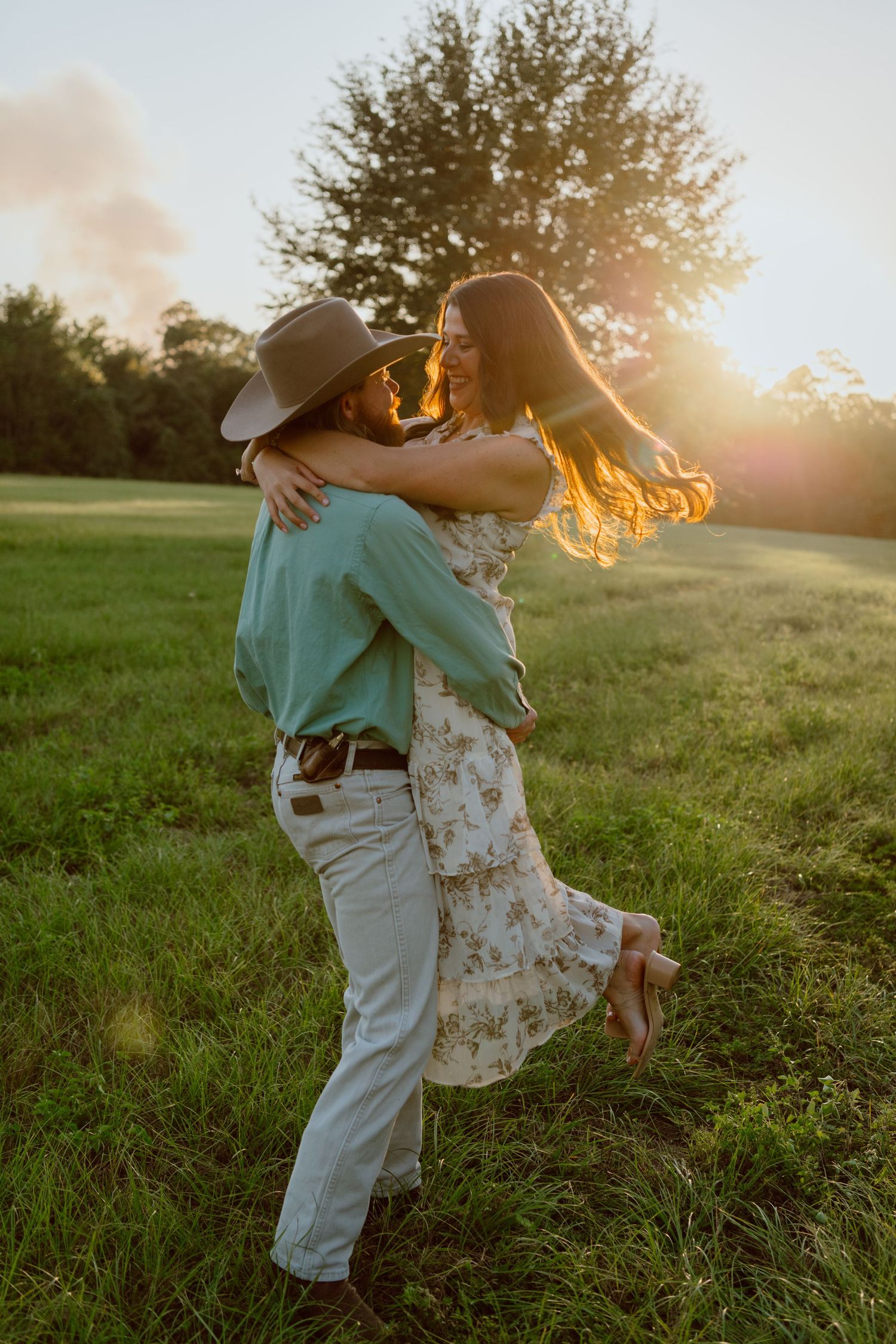 Couple in casual attire walking together through autumn field at sunset.