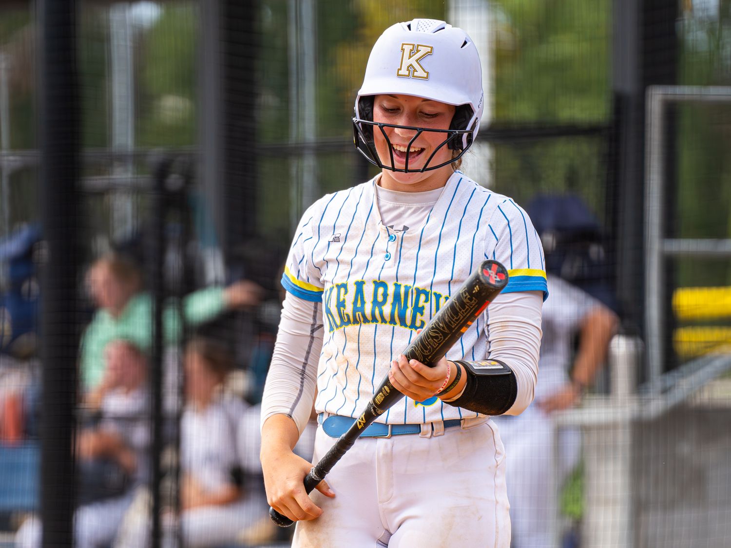 Softball batter in pinstripe uniform prepares to hit during game.