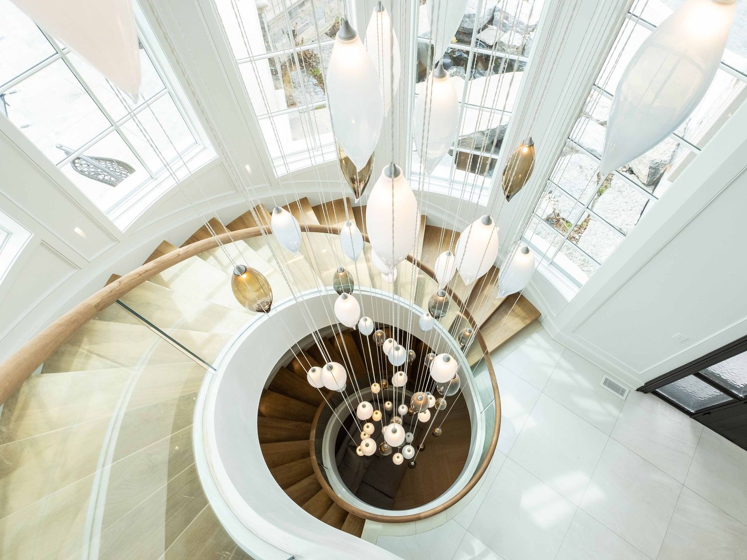 Spiral staircase with modern chandelier and white interior design elements.