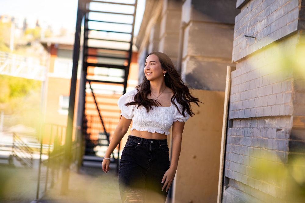 A person in a white crop top and dark pants enjoying a carefree moment outdoors in golden sunlight.