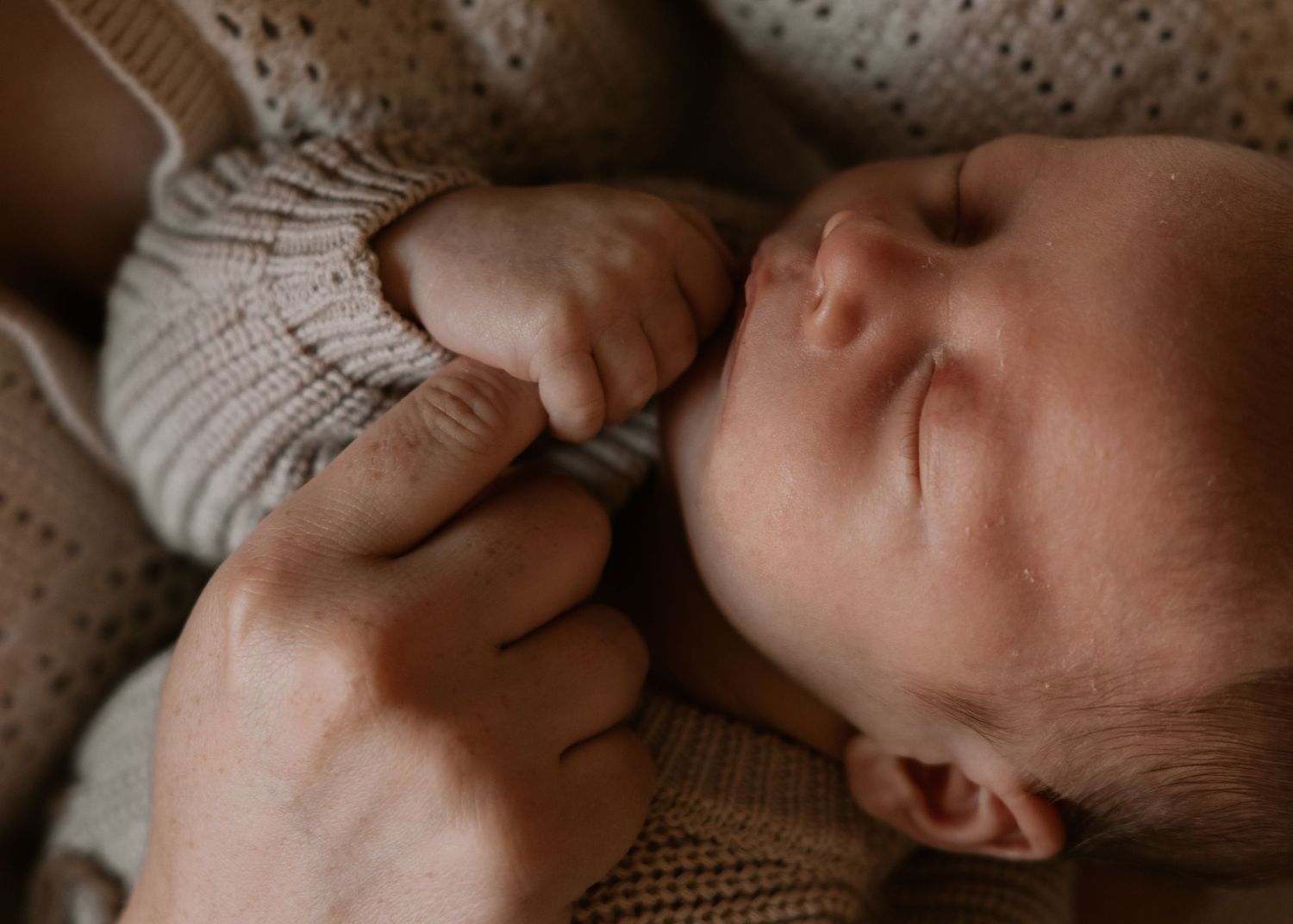 Newborn baby on a plush sheepskin rug, bathed in natural light during an in-home newborn photoshoot in Wollongong.