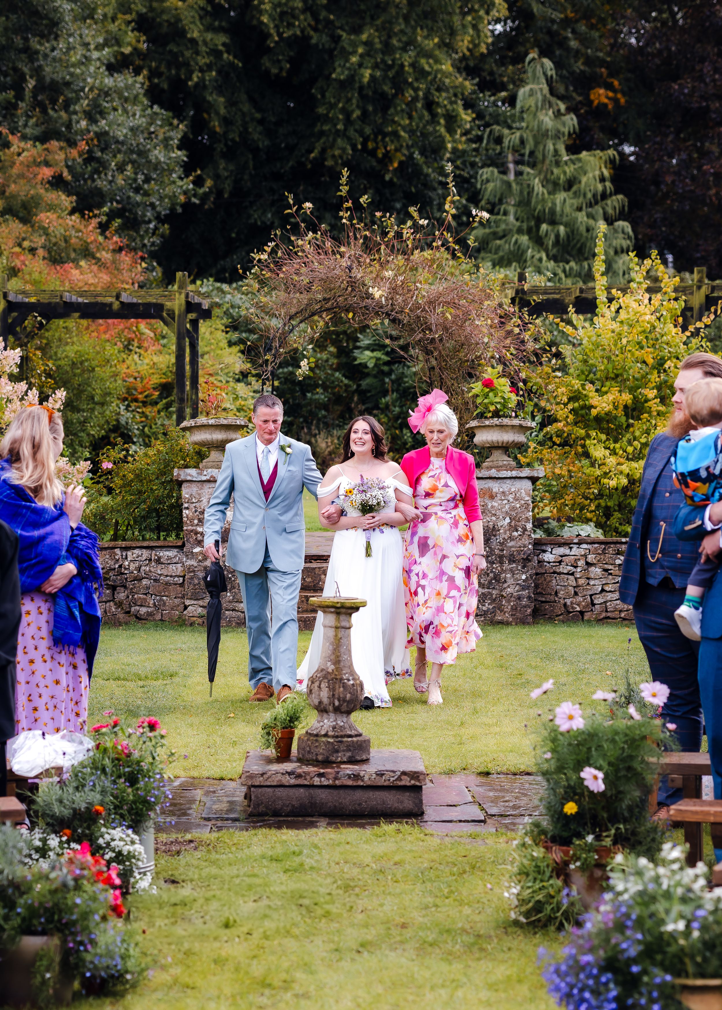 non-traditional wedding photographer in the Lake District - bride walking down the aisle with mum and dad