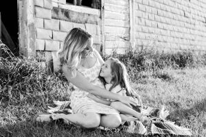 Black and white photo of a mother and daughter sharing a tender moment outdoors.
